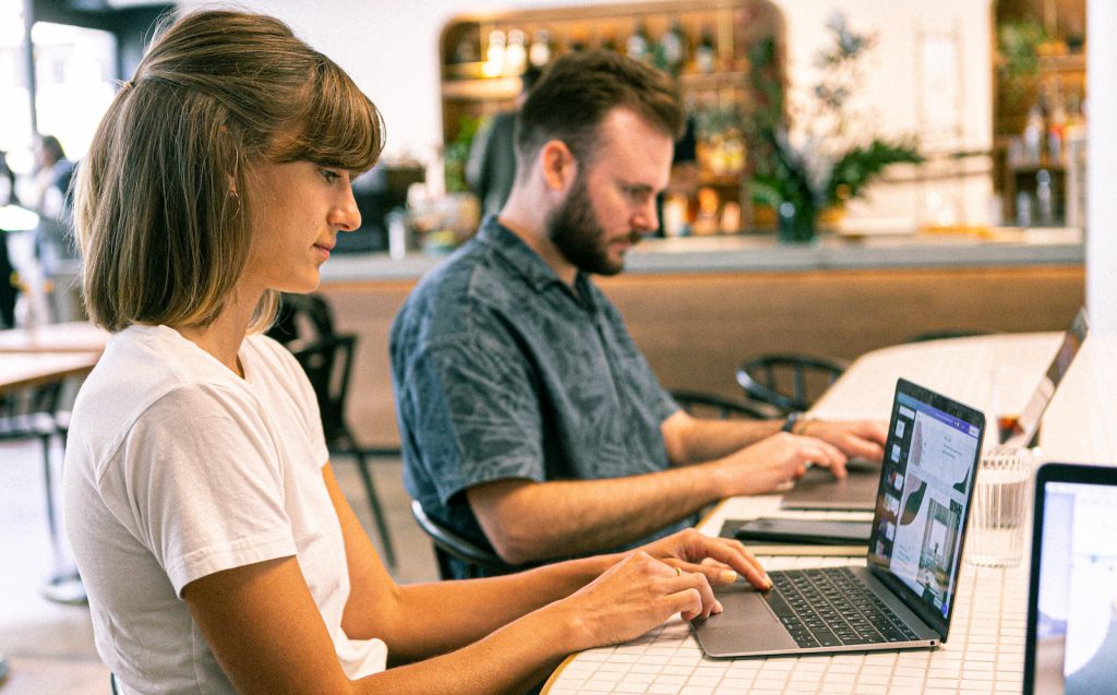 Two people sitting at a table using laptops